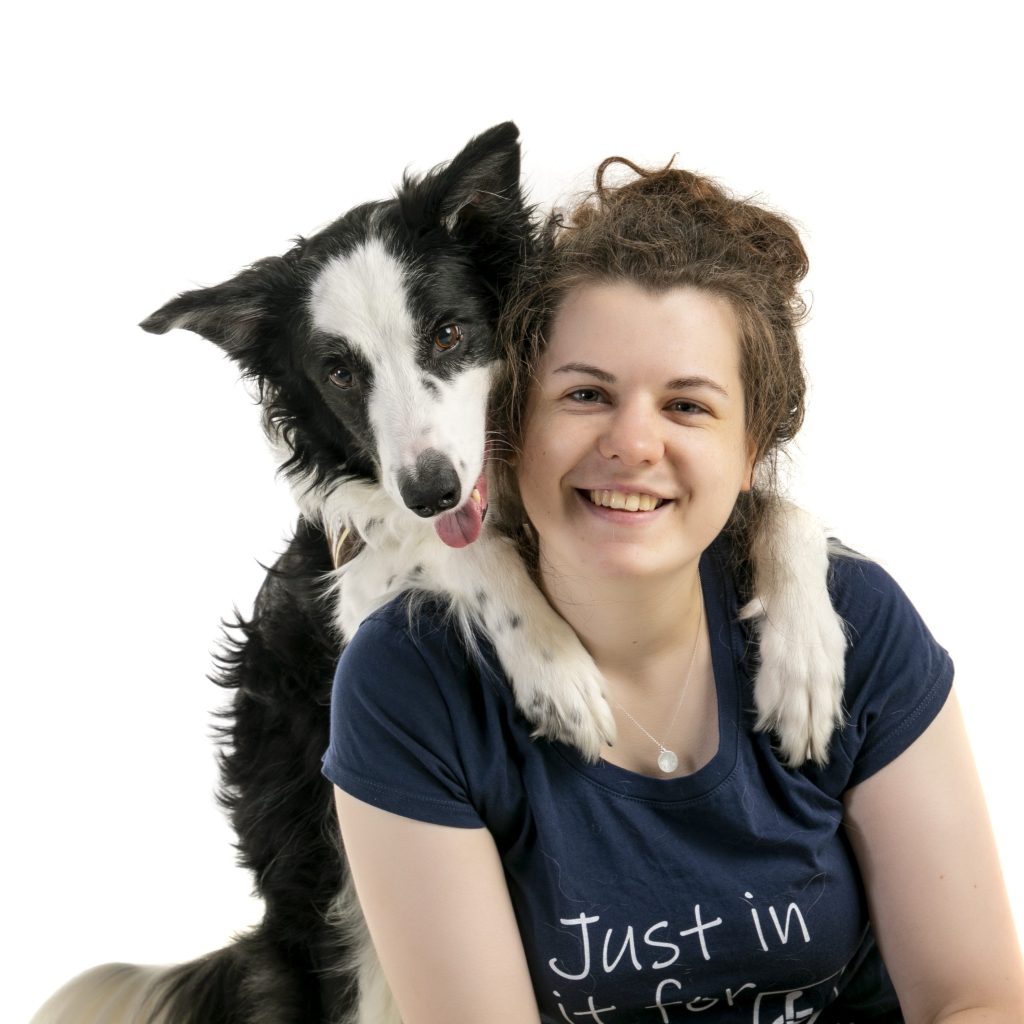 A black and white border collie with his paws on the shoulders of a white woman